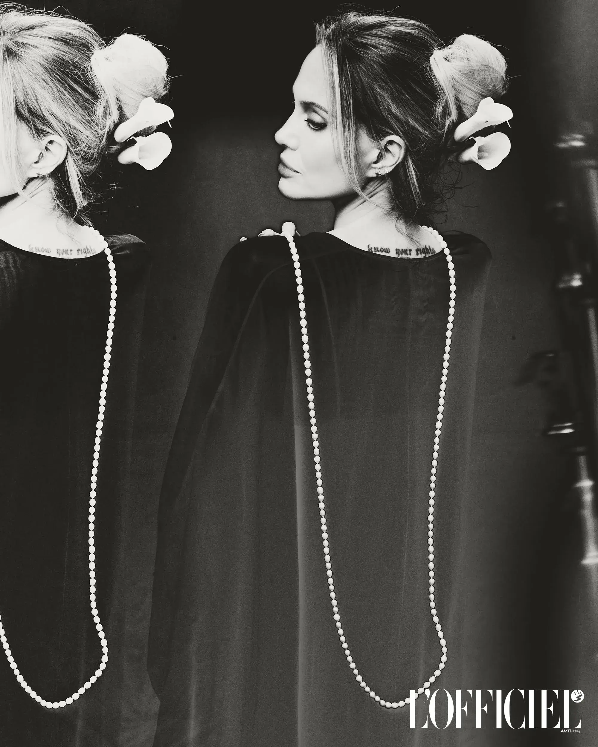Black and white portrait of Angelina Jolie wearing a pearl necklace and flowers in her hair for L'Officiel Italia.