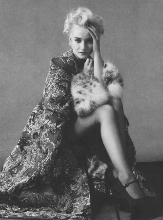 Portrait of Julia Garner seated in a patterned coat against a plain backdrop for Elle U.S. editorial.
