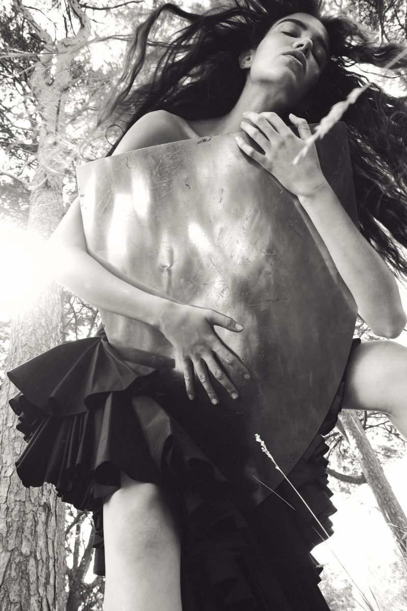 Model holding a metallic sheet outdoors among trees for Pop Magazine, photographed by Oliver Hadlee Pearch.