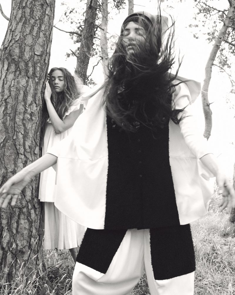 Two female models posing among pine trees outdoors in a black and white fashion editorial by Oliver Hadlee Pearch for Pop Magazine.