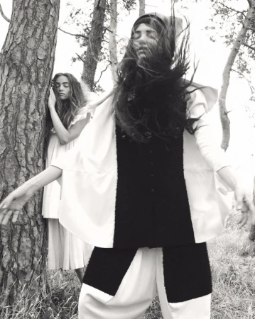 Two female models posing among pine trees outdoors in a black and white fashion editorial by Oliver Hadlee Pearch for Pop Magazine.
