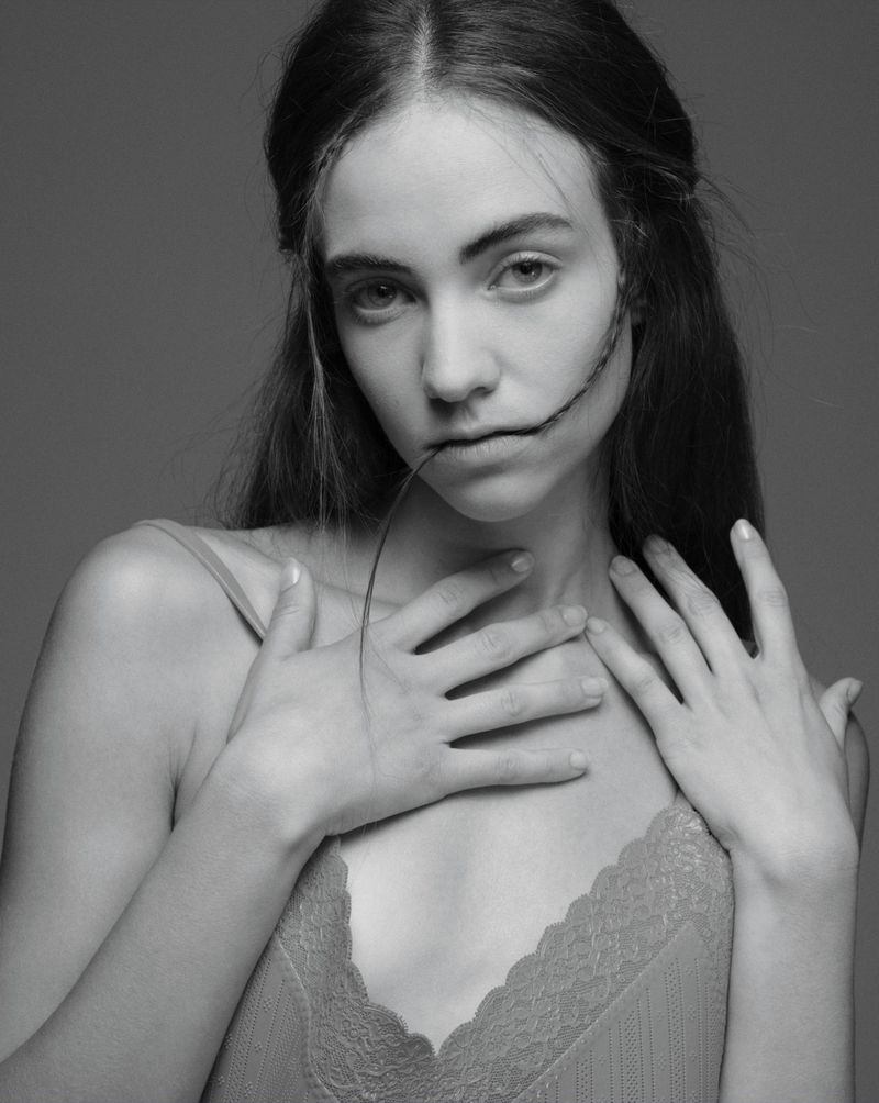 Monochrome portrait of Grace Hartzel with hands near her chest biting a strand of hair for Pop Magazine editorial.