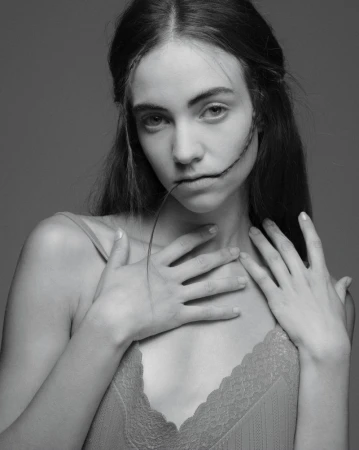 Monochrome portrait of Grace Hartzel with hands near her chest biting a strand of hair for Pop Magazine editorial.