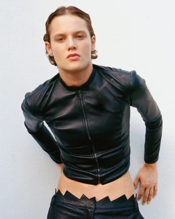Model in black leather zip jacket and zig-zag waistband pants posing against a plain white background for The Gentlewoman.