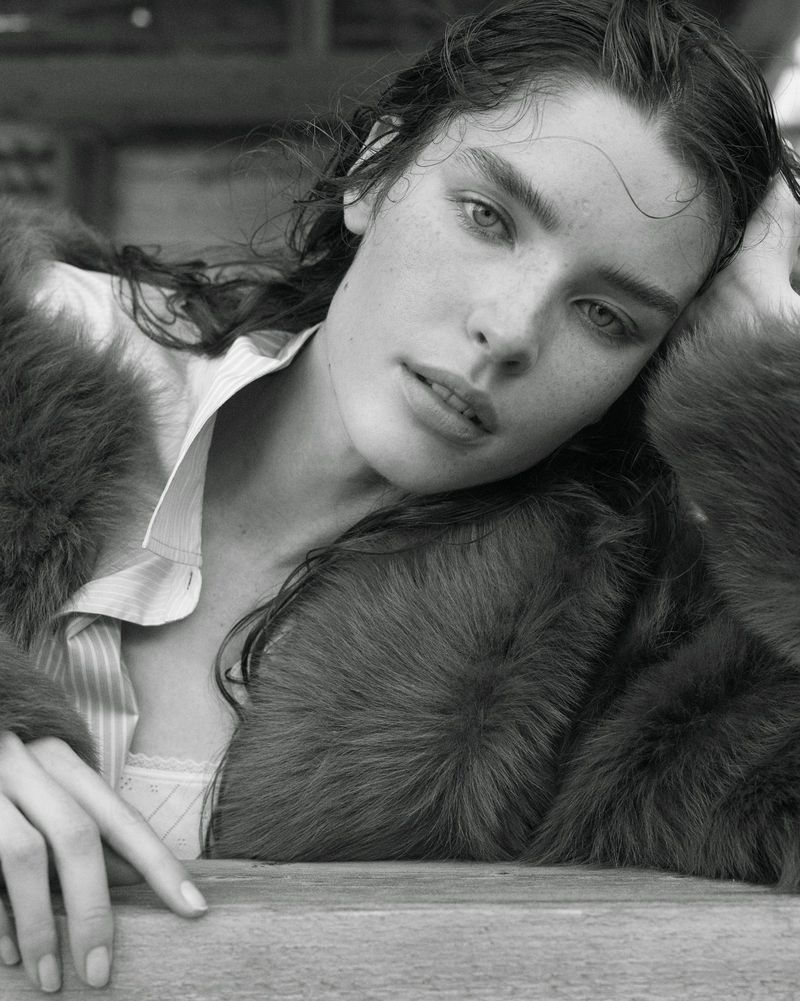 Black and white portrait of a model with wet hair wearing a fur coat and collared shirt