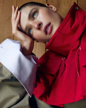 Portrait of a model wearing a red jacket and white cuff against a wood panel wall, photographed by Karim Sadli for The Gentlewoman.