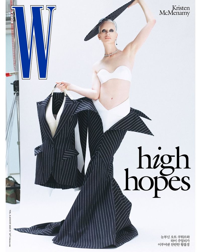 Fashion magazine cover featuring a stylish model wearing a white bandeau top and pinstripe skirt, holding a pinstripe suit jacket.