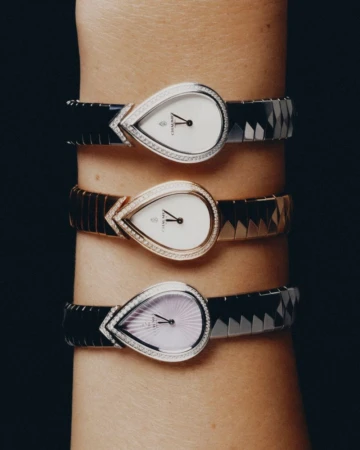 Close-up of a wrist wearing three teardrop-shaped luxury wristwatches against a dark background.
