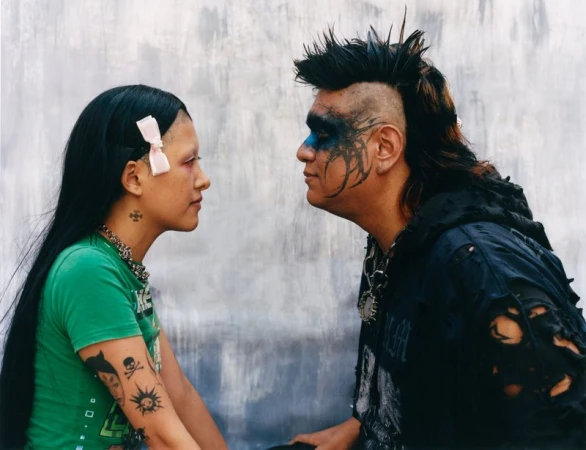 Two people facing each other with distinct alternative styles against a textured concrete background for 72 Magazine Multiverso.