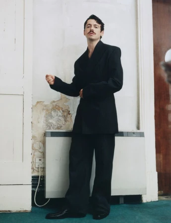 Anthony Boyle wearing an oversized black blazer and trousers standing in an interior space for HERO Magazine