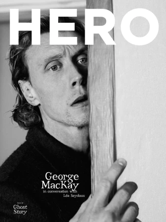 Portrait of actor George MacKay peeking around a doorway in a monochrome magazine cover for HERO Magazine.