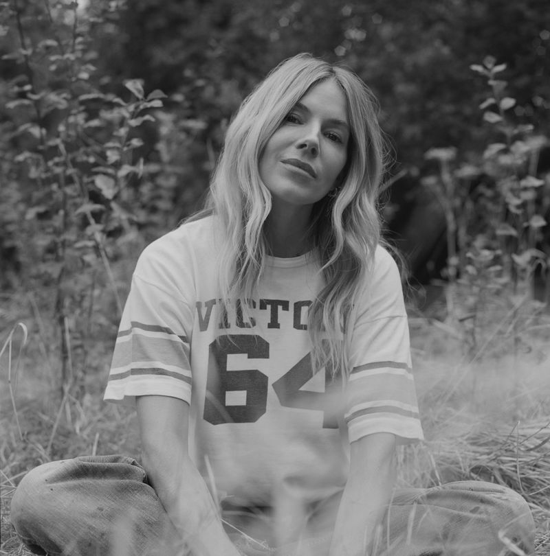 Portrait of actor Sienna Miller seated outdoors wearing a graphic t-shirt in a black and white editorial photograph