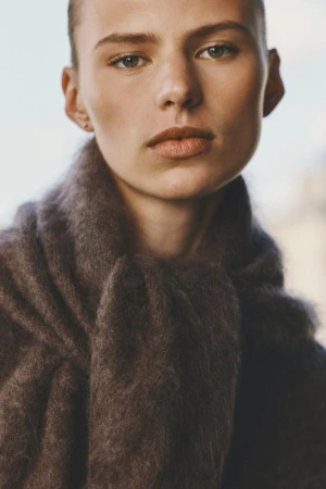 Close-up portrait of a woman wearing a thick textured dark brown scarf for H&M shot by David Portela