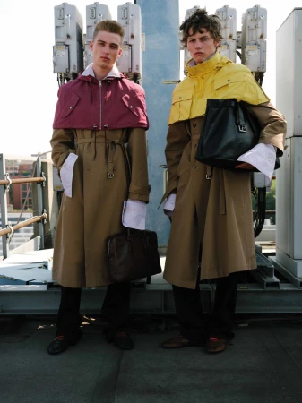 Two male models in long tan coats standing on a rooftop holding bags for U Repubblica Miles from here editorial.