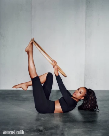 Kerry Washington lying on studio floor holding a pilates ring while wearing black activewear for Women's Health U.S.
