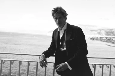 Man in a tuxedo leaning on a white railing overlooking the ocean for the Brunello Cucinelli project Midnight Silence