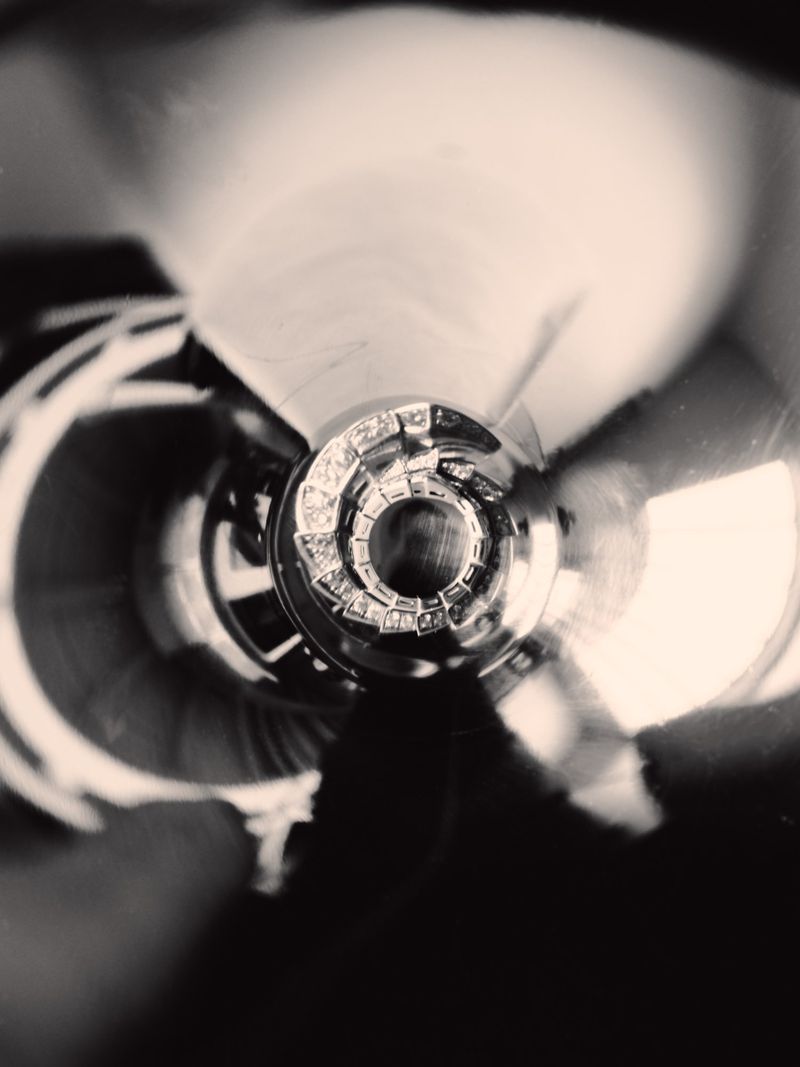 Monochrome abstract close-up macro view featuring a metallic spiraling structure with concentric circular patterns and high contrast tones.