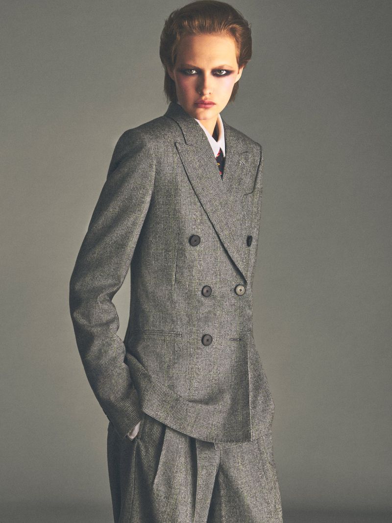 Model wearing a grey double-breasted tweed suit against a neutral studio background