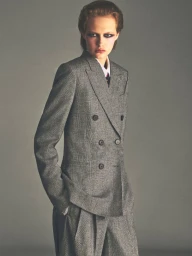 Model wearing a grey double-breasted tweed suit against a neutral studio background