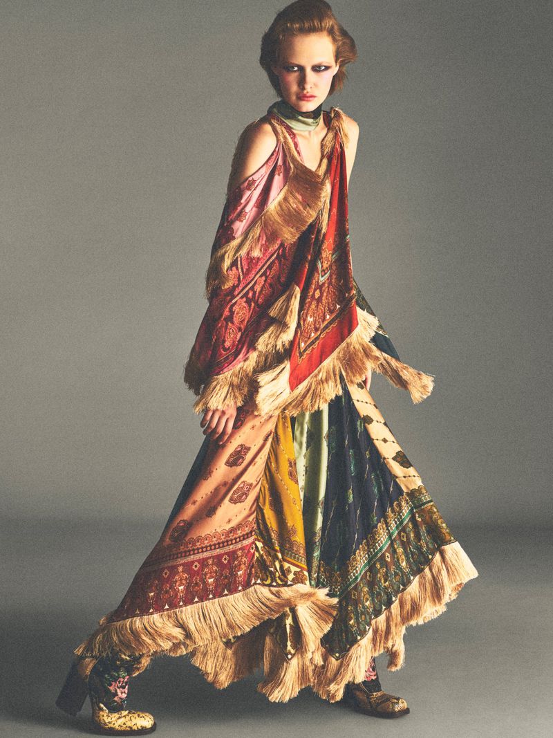 Model in a patterned fringe dress posing against a grey studio background for Vogue France by Allan Hamitouche.
