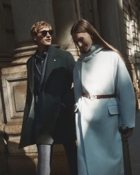 A man and woman walking together past a classical stone building exterior for Manuel Ritz FW26 campaign.