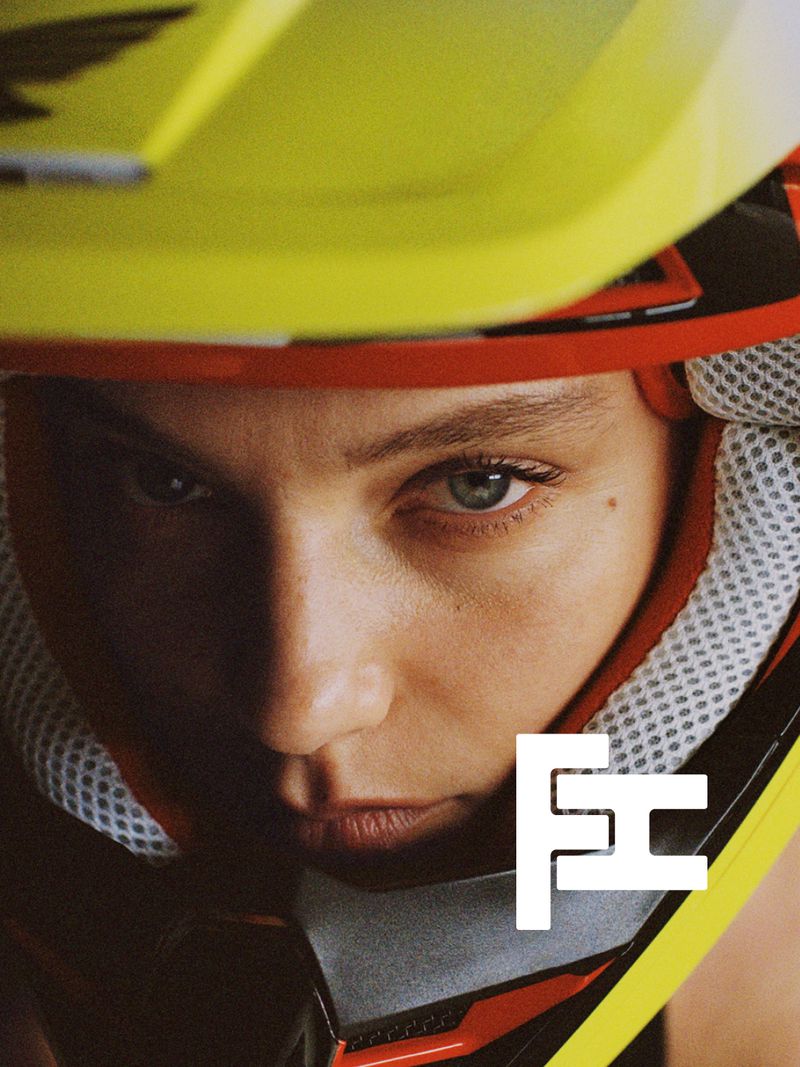 Close-up portrait of a model wearing a yellow and red motorsport helmet for Fara Homidi