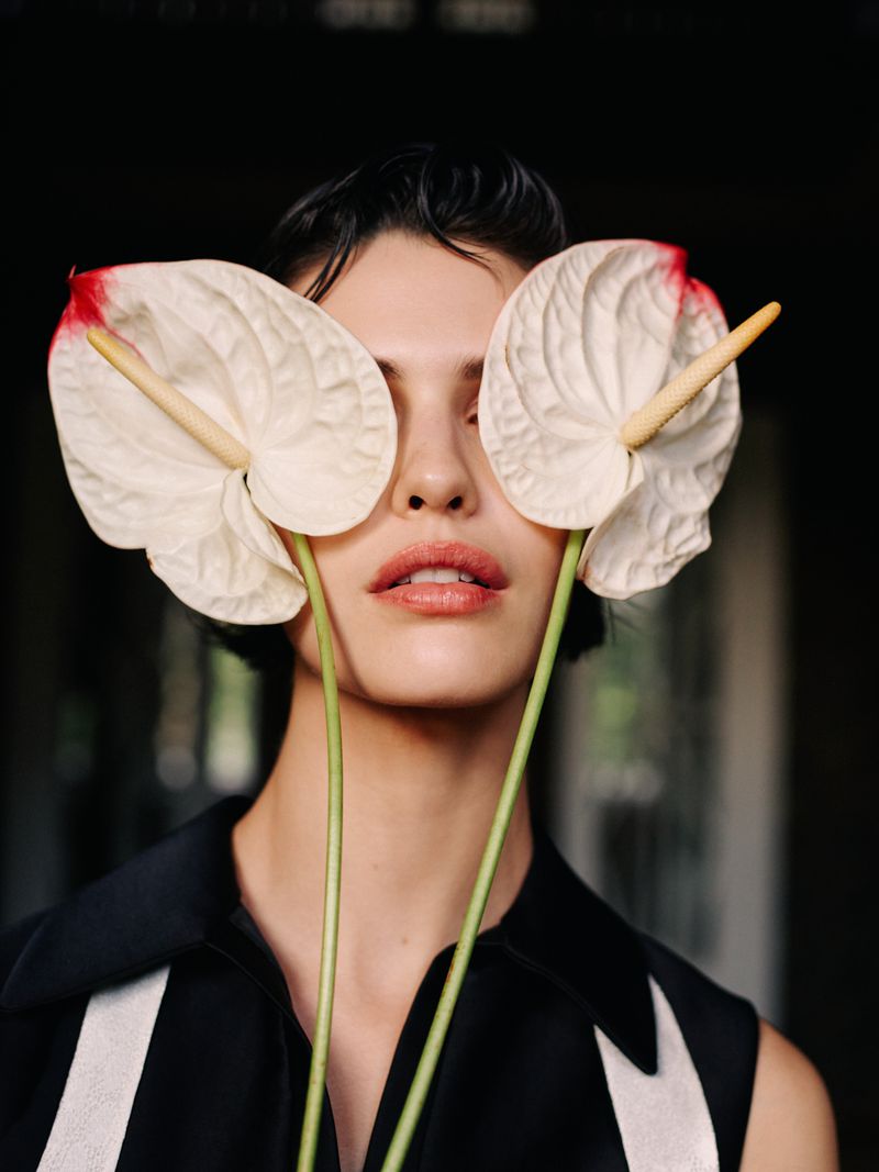 Model Marta Buiko holding white anthurium flowers over her eyes for Elle Czech Republic project The Bohemian Romance