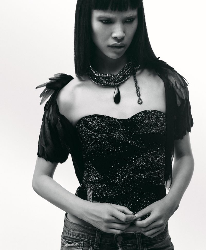 Model Diane Chiu in a black strapless embellished top and layered pendant necklace against a plain white background