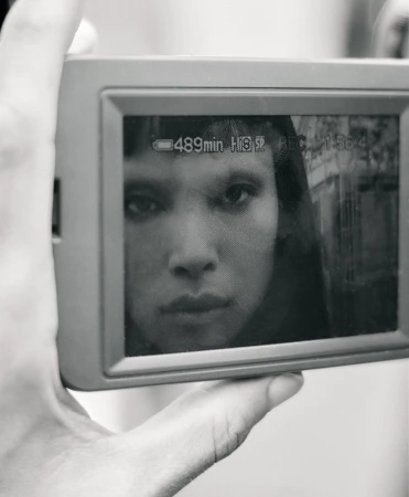 Close-up of a person holding a digital camera displaying a black and white portrait of model Diane Chiu on screen.