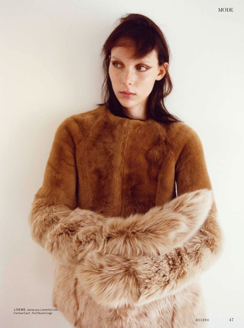 Model wearing a brown shearling jacket with fluffy cuffs posing against a plain white background for Bolero Magazine.