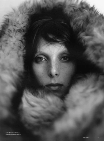 Close-up monochrome portrait of a model framed by a voluminous textured faux fur hood.