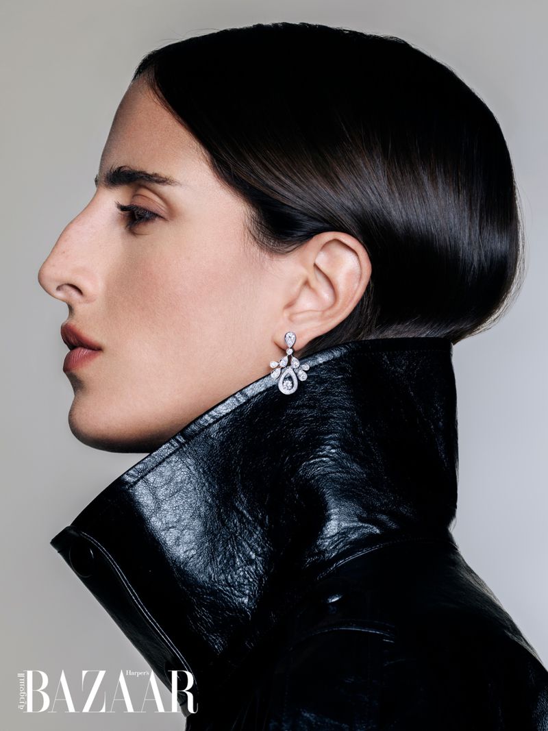Model Taleedah Tamer in profile wearing a black patent leather coat and diamond earrings for Harper's Bazaar Arabia.
