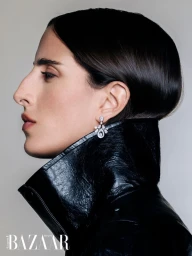 Model Taleedah Tamer in profile wearing a black patent leather coat and diamond earrings for Harper's Bazaar Arabia.