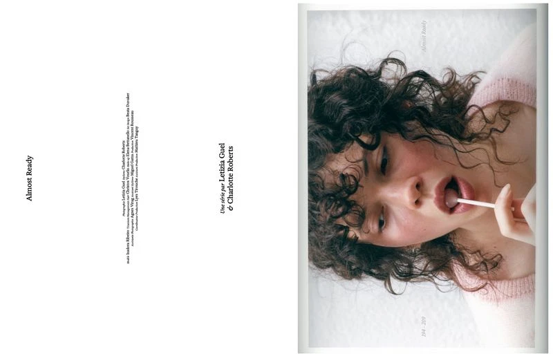 Close-up portrait of a curly-haired woman holding a lollipop, styled with a pink knit top for COEUR - ISSUE II editorial