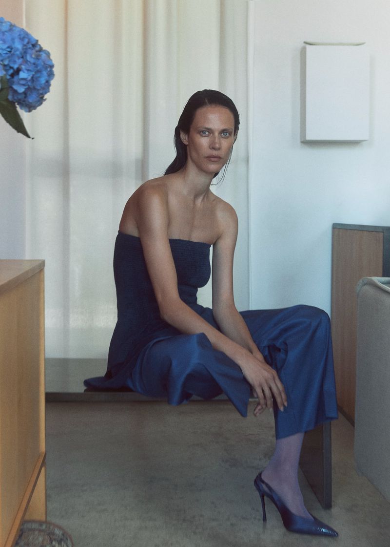 Model Aymeline Valade wearing a blue strapless top and matching trousers sitting indoors