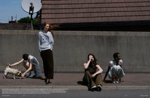 Four models outdoors against a concrete wall and pavement, featuring a standing red-haired woman and a small dog on a leash.
