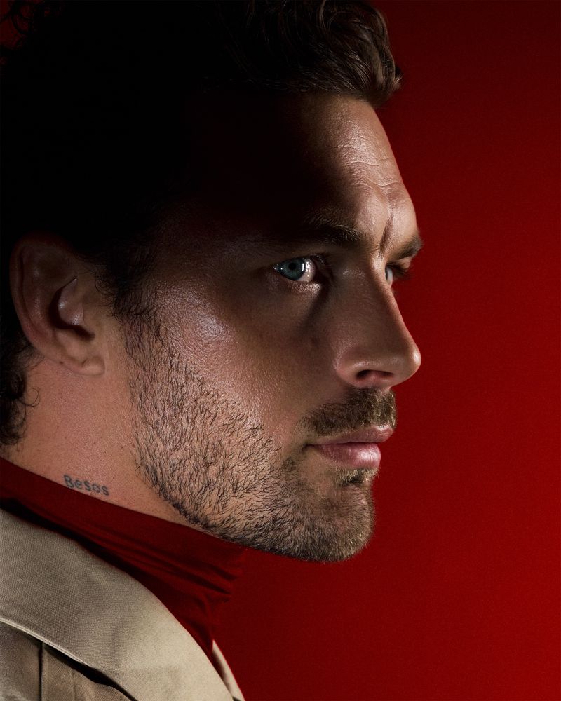 Profile portrait of model Christian Hogue wearing a red turtleneck against a rich red background for TMRW Magazine