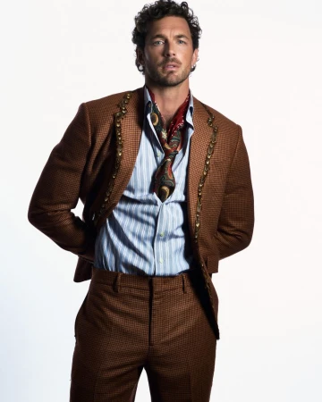 Model Christian Hogue wearing a patterned brown suit and striped shirt for TMRW Magazine.