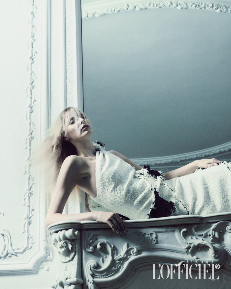 Model in white textured dress reclining on an ornate mantelpiece for L'Officiel Italia editorial