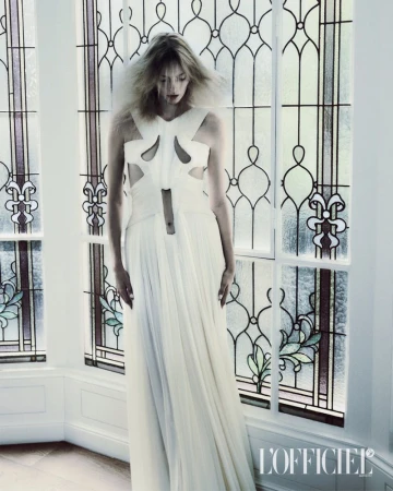 Model Elza Matiz in a white cutout dress standing before large stained glass windows for L'Officiel Italia.