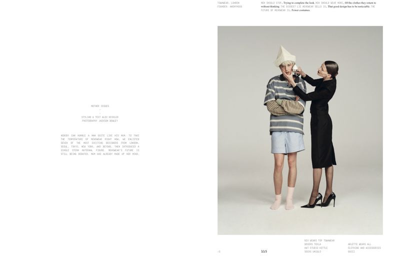 Two models posing in a studio with a grey seamless background, featuring a woman in a black dress touching a man wearing a paper hat.