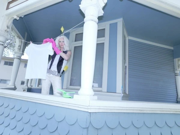 Blonde model hanging a white t-shirt on a clothesline on a blue porch for Rouge Fashionbook