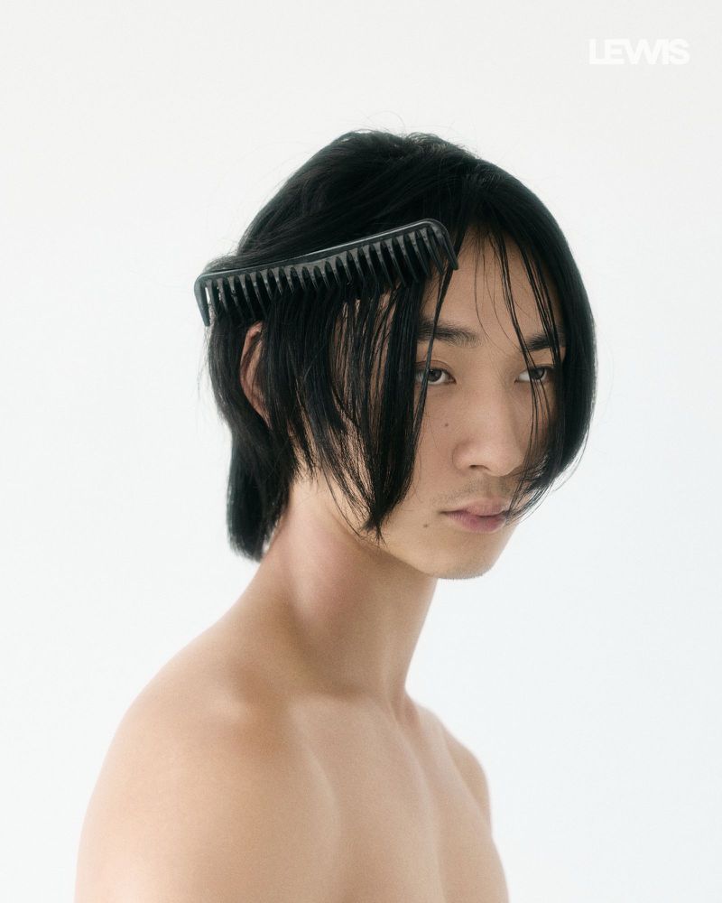 Portrait of an Asian man with black hair wearing a black comb tucked into his hair against a plain white background