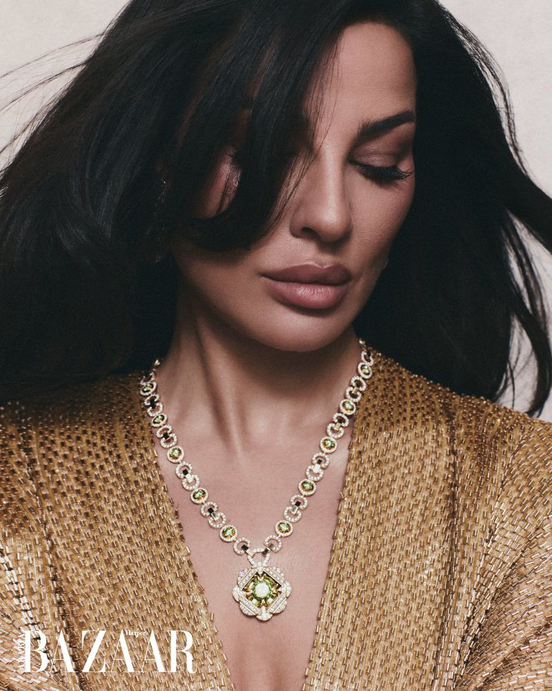 Close-up portrait of a woman wearing a gold necklace and textured top for Harper's Bazaar Arabia