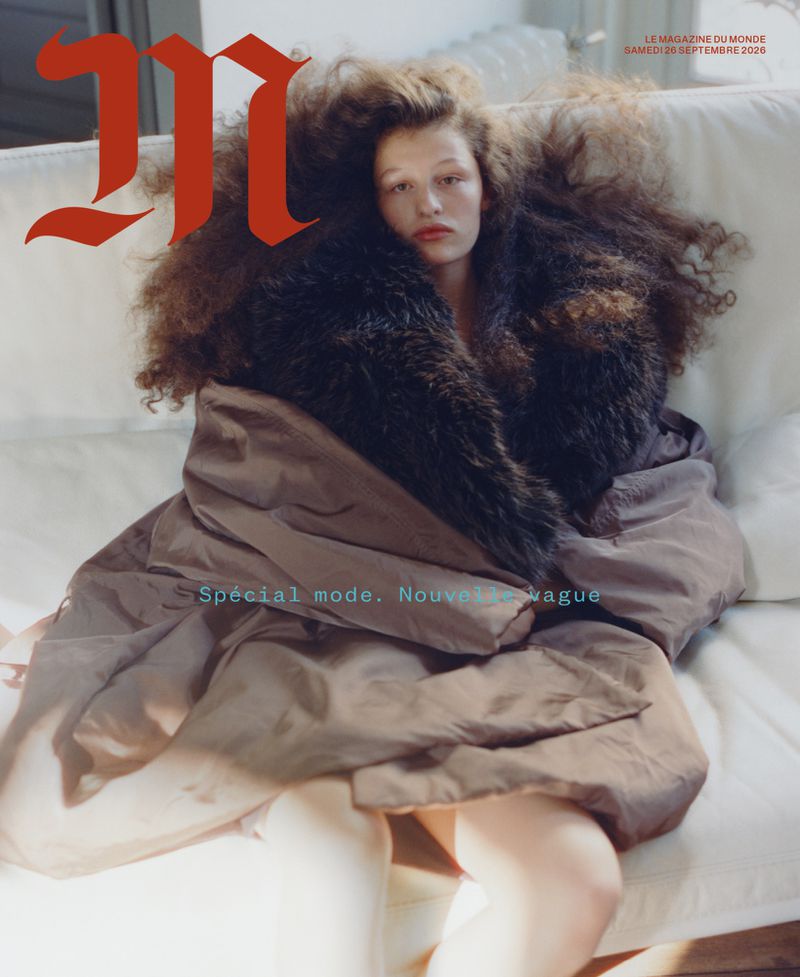 Model Athena Accorsi-Casta seated on a white sofa wrapped in a large brown coat with fur collar, photographed by Senta Simond for M Le magazine du Monde.
