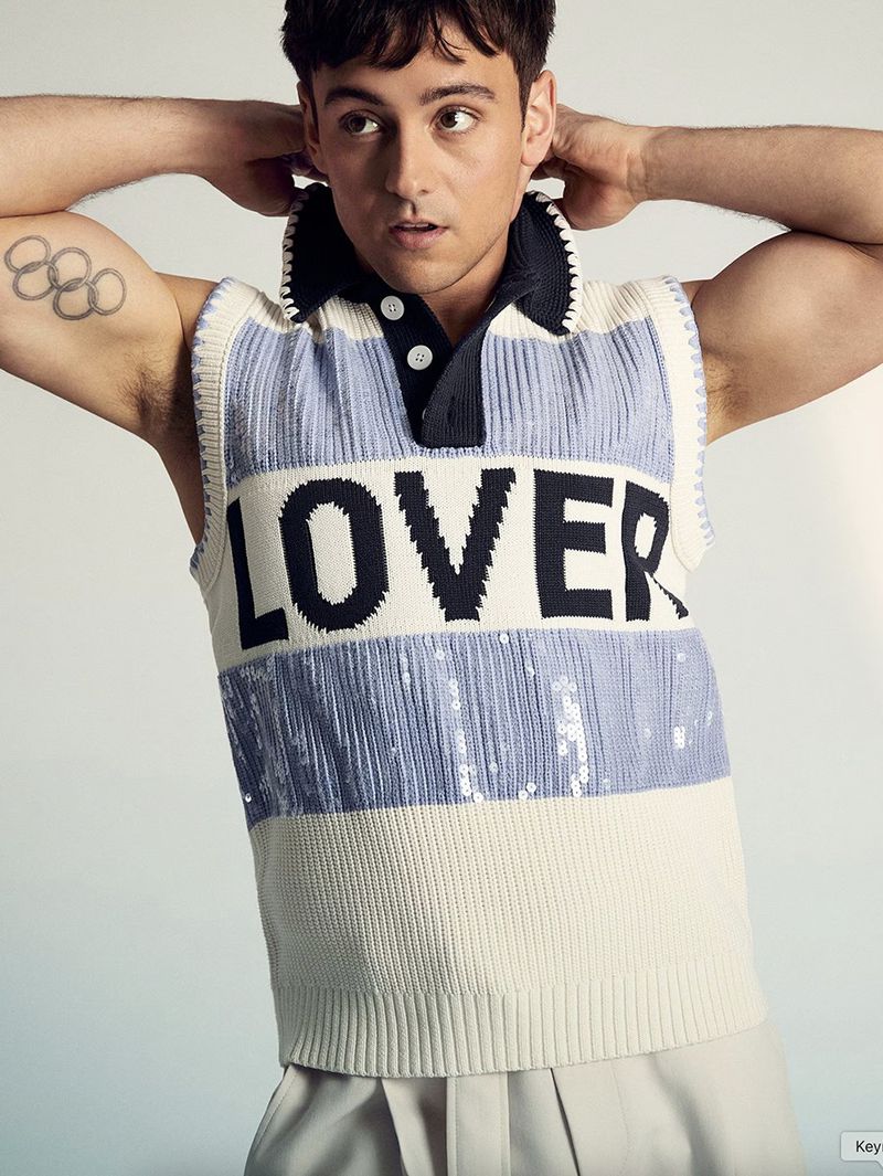 Portrait of a young adult male wearing a sleeveless collared shirt with the word 'LOVER' against a neutral background.