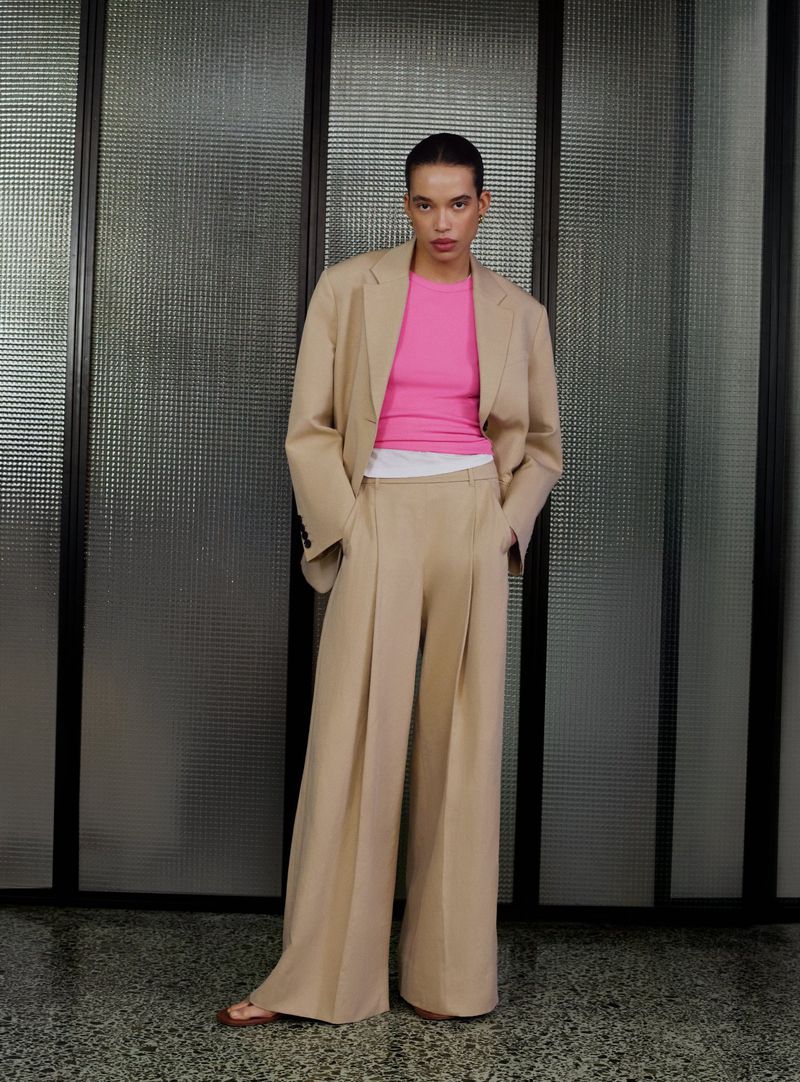 Model Lara Menezes wearing a camel trouser suit and pink top standing indoors for ME+EM June Lookbook