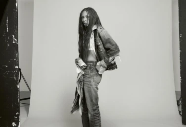 Portrait of Ravyn Lenae wearing denim jacket and jeans against a white seamless backdrop for Heroine Magazine.