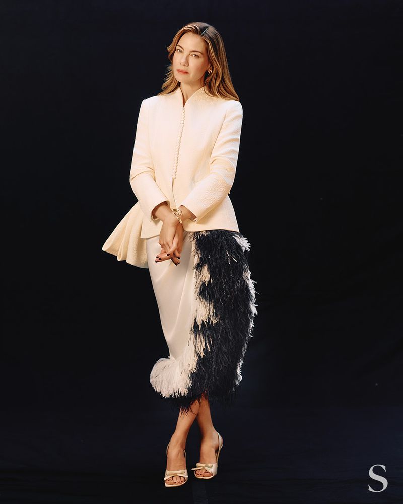Michelle Monaghan wearing a cream jacket and feathered skirt against a black background for S Magazine editorial