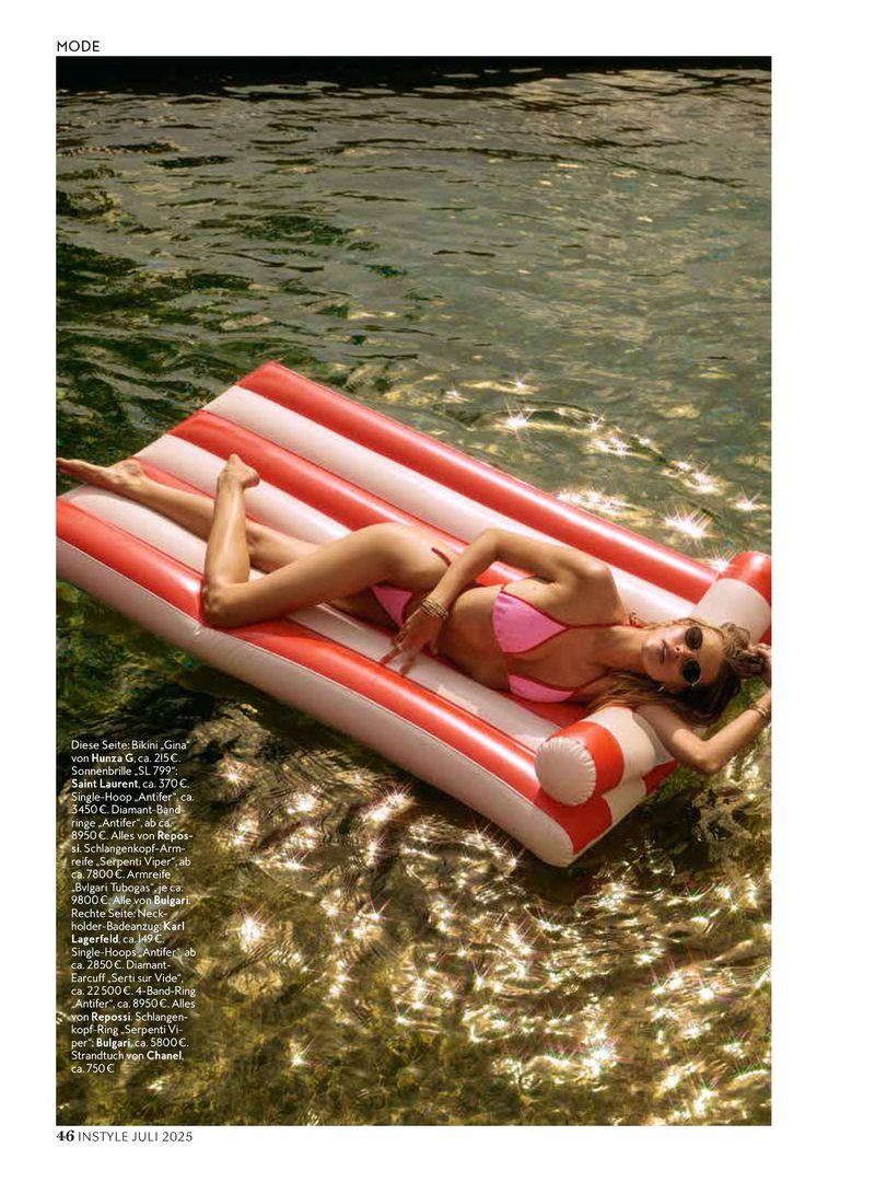 Woman in pink bikini and sunglasses relaxes on red and white inflatable raft in shimmering water, enjoying summertime leisure.